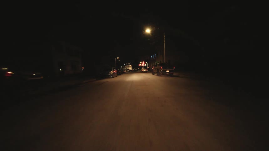 Cars line a street with very few street lights