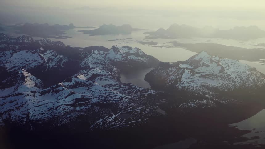 Mountains near a large body of water are covered with snow on the peaks