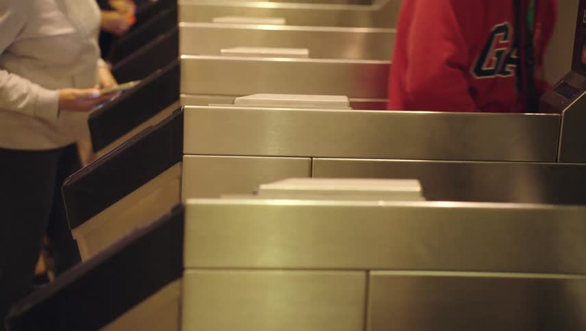 Some people who swipe their cards at turnstiles to get to the other side