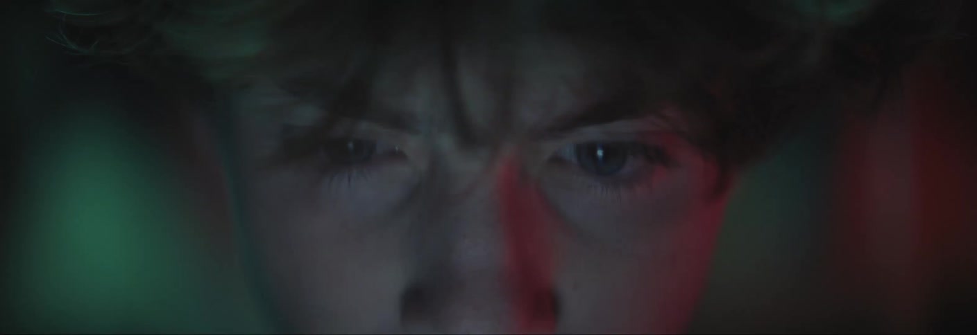 Youth frowns while using a computer at night