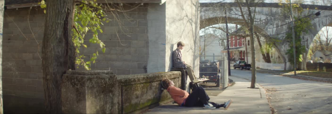 Two friends hang out on the sidewalk and talk