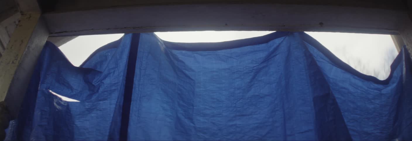 Upward view of a wooden architecture with a blue tarpaulin