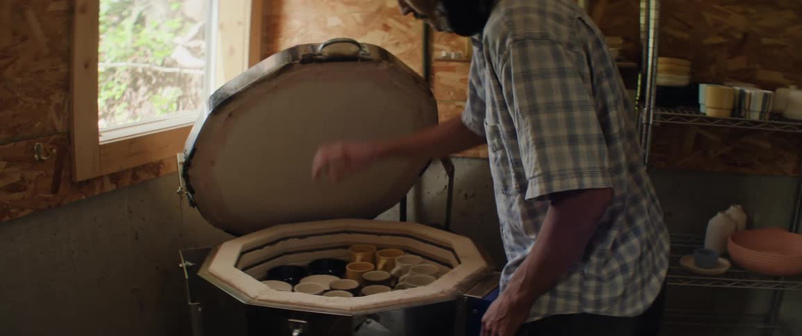 A man removes finished ceramics from a kiln to examine
