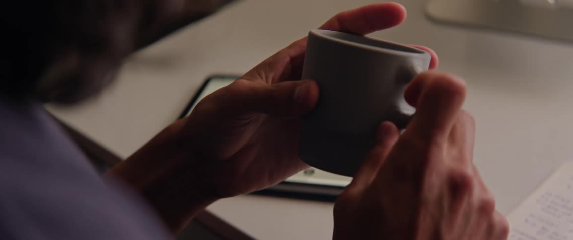 A person examines a mug design while using a tablet