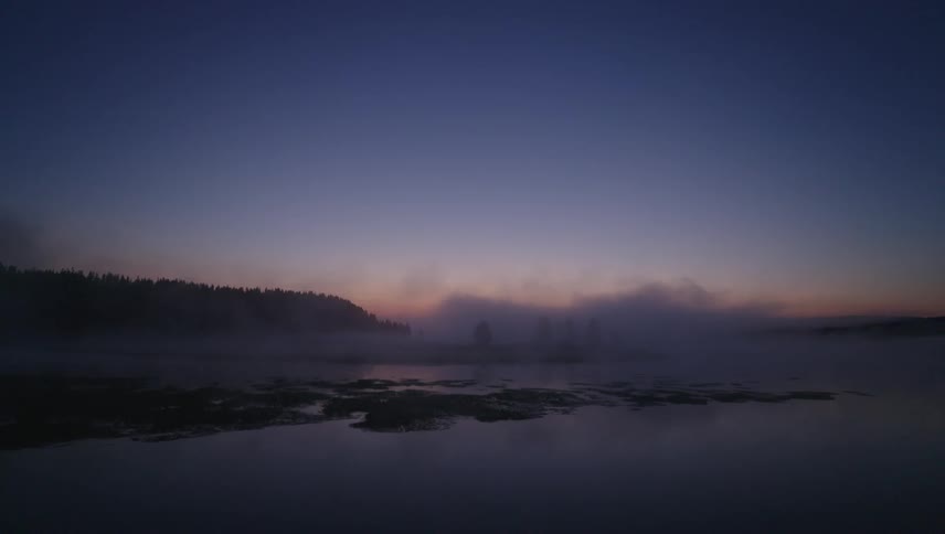 The fog rolls over the water at sunrise