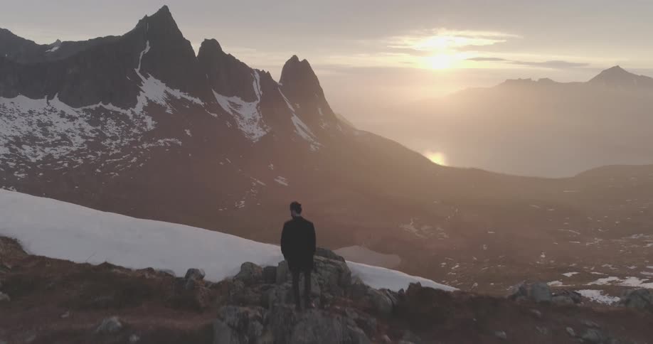 Man standing on the mountain range looking towards the horizon