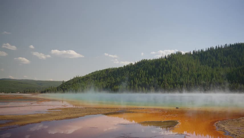 Landscape of a lake with thick smoke and mountains with conifers in the background