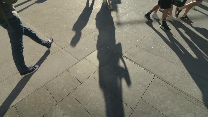 Shadows of people walking across a sidewalk in the city