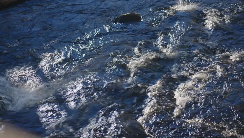 A closeup of a rushing river with the water churning and creating whitecaps