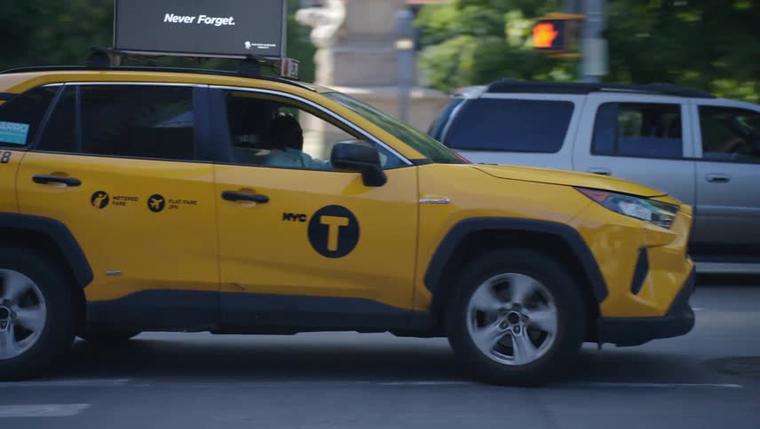 A yellow taxi cab is driving through an intersection in an urban area