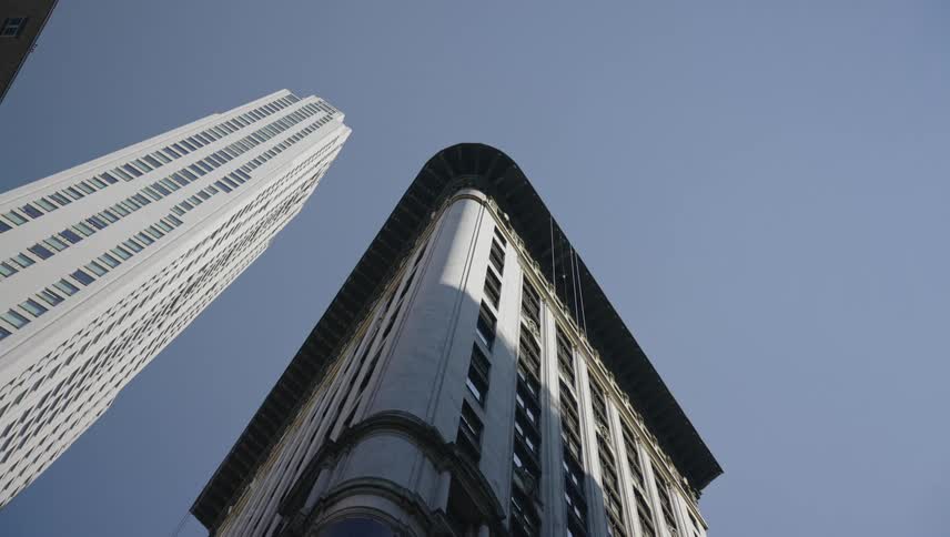 A tall modern skyscraper dominates the skyline towering over a shorter older building with ornate architectural details
