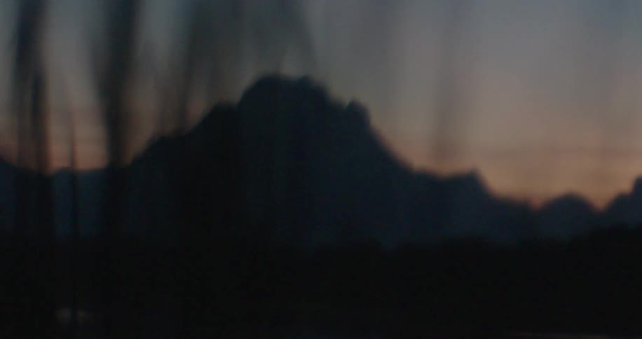 Past the grass is a mountain in the shade