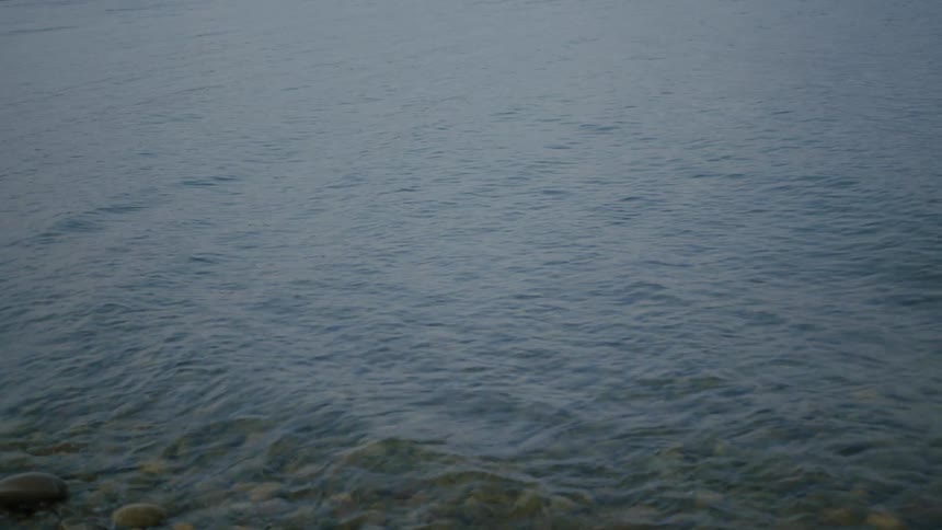 Some small waves breaking on a coast full of round pebbles