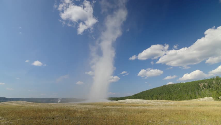 Landscape of smoke rising from a ground surrounded by mountains and forests