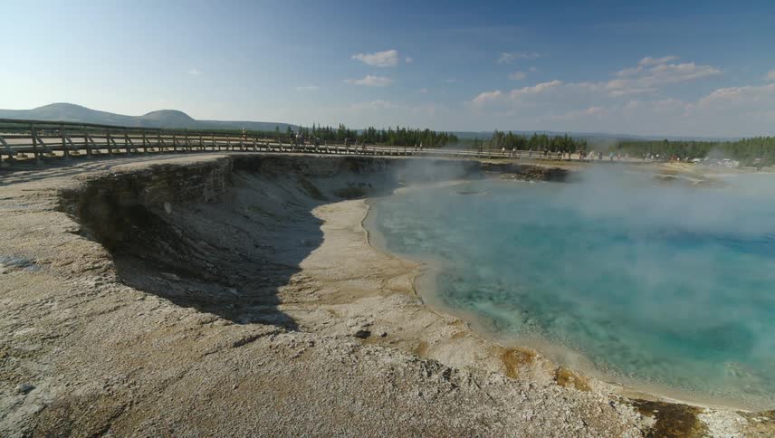 People are hiking on a path by the hot spring