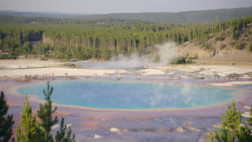 Tourists walk along a boardwalk near hot springs in yellowstone national park