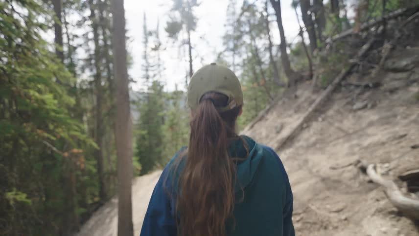 Woman walking along a trail surrounded by trees