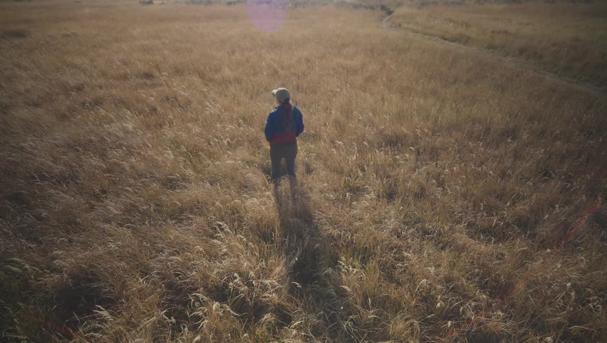 A woman is standing on the field on a sunny day