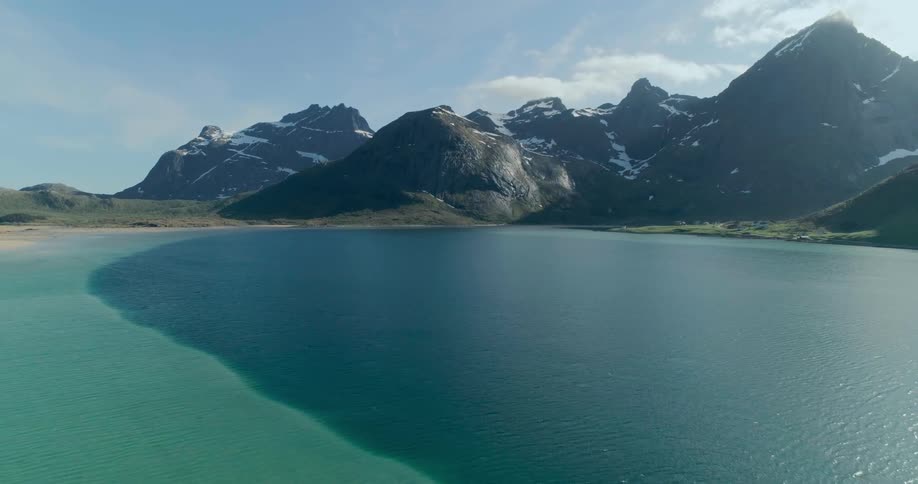 A coastal landscape with snowcapped mountains framing a turquoise bay of the lofoten islands in norway