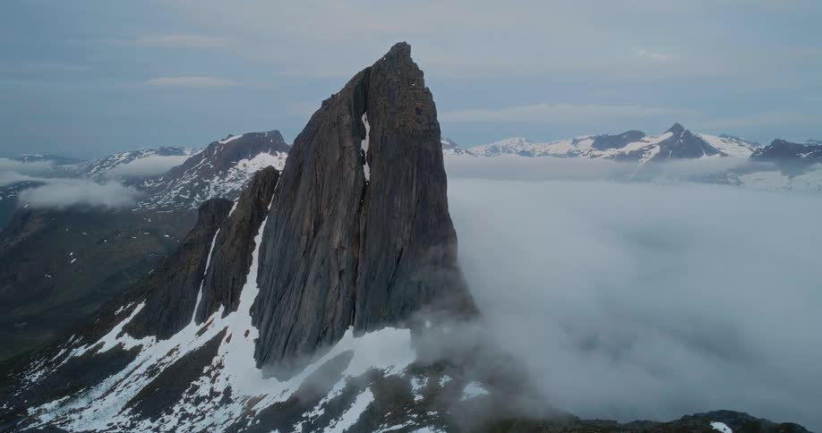 Aerial view of a mountain peak its jagged summit piercing through a sea of clouds creating a scene of aweinspiring natural beauty