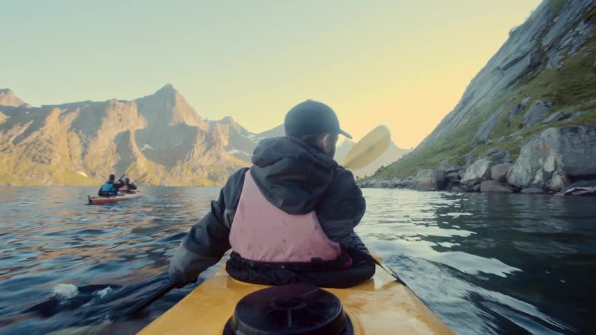 A group of people kayaking on a calm lake in the mountains at morning