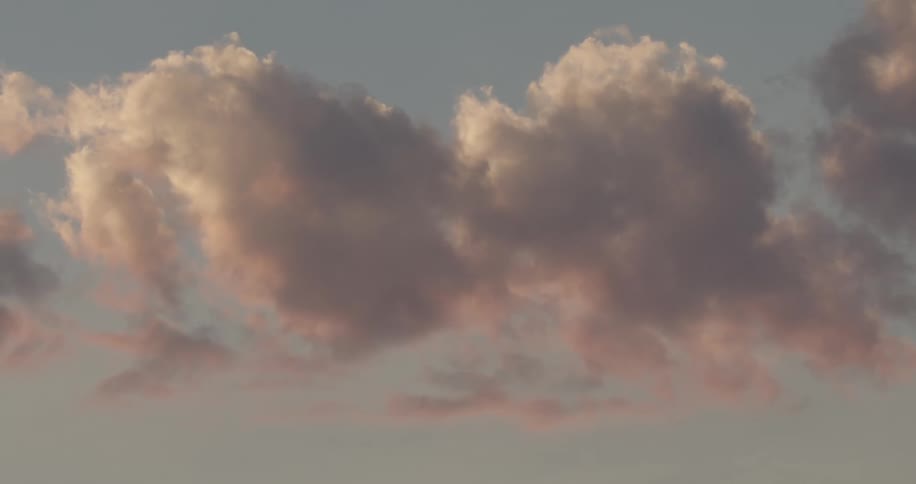 Large red tinted clouds float through the light blue sky
