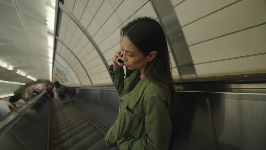 Woman on an escalator talking on her smartphone on a call