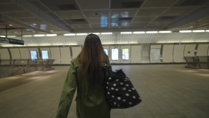 Woman rushes through times square grand central station with a large bag