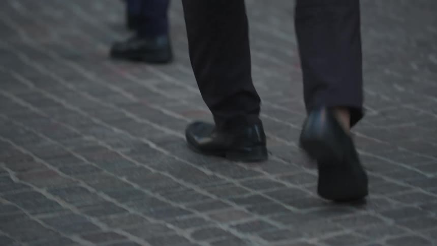 People are walking together on the cobblestone sidewalk