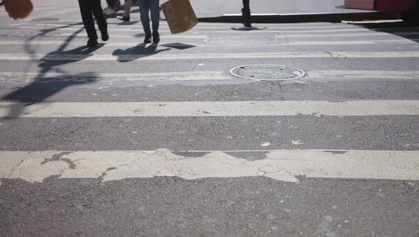Some pedestrians passing through a crosswalk on an asphalt floor