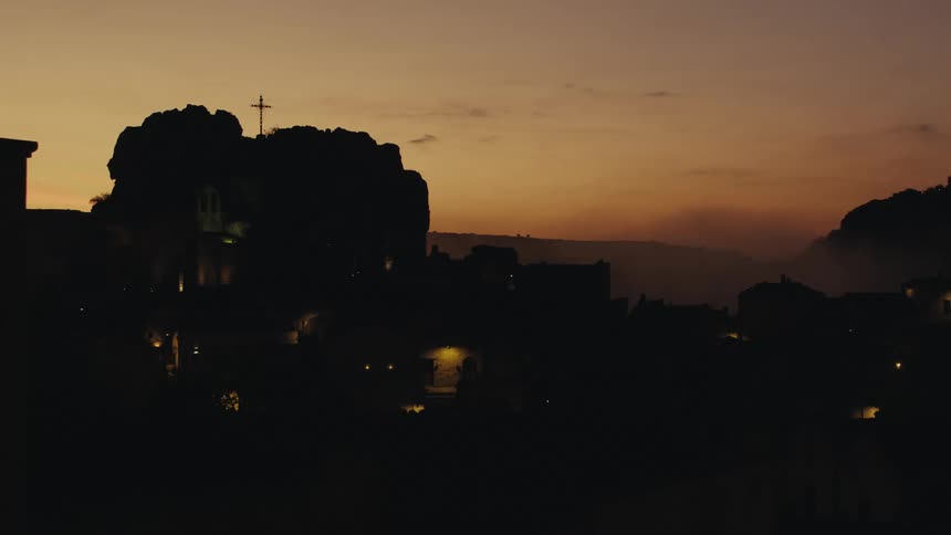 Urban city with silhouette of trees and mountains in a reddish sky dawn