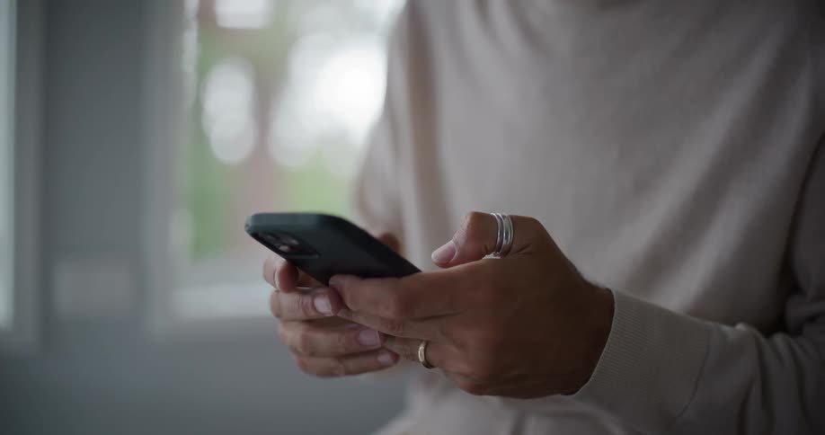 Man fingers with rings are actively typing on the screen suggesting they are engaged in browsing online