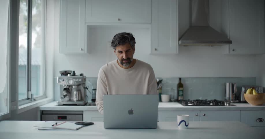 Man in kitchen interacting with a laptop