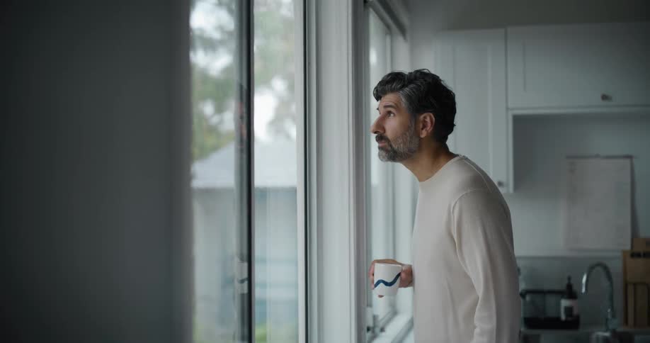 Man in the kitchen drinking from a mug