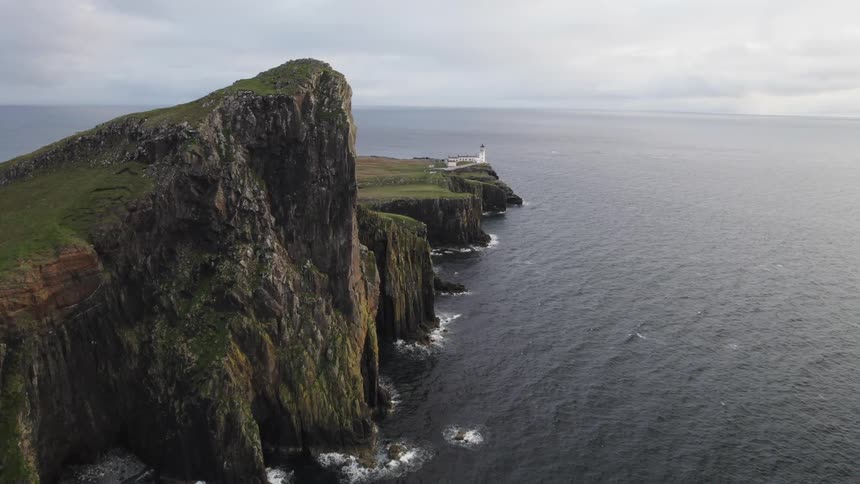 A lighthouse stands perched precariously on the edge of a dramatic cliff overlooking a vast ocean