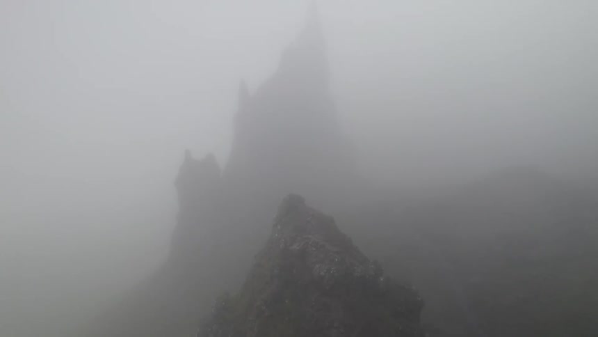 A rocky peak emerges from a thick fog