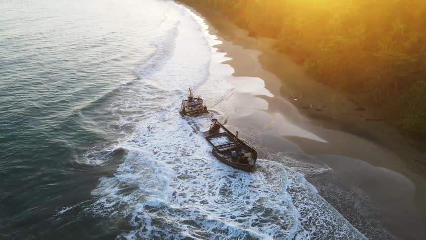 A weathered shipwreck rests on the beach battered by the waves