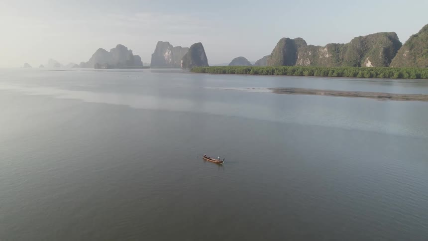 Aerial view of a canoe isolated in the sea with mountains in the background