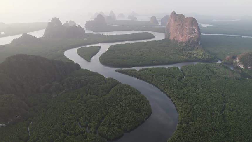 An aerial view of a river with several stretches and many forests of trees next to huge rock formations