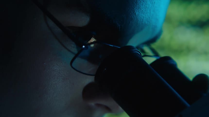Female scientist is looking at the microscope and analyzing the result