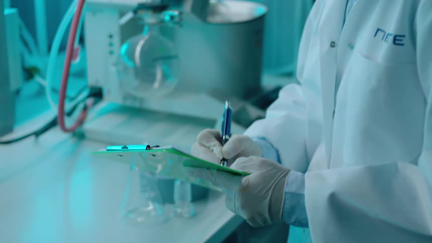 Woman in a laboratory taking a note with a pen