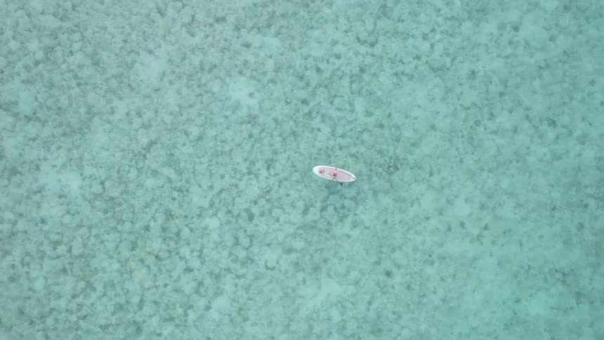 Birds eye view of a person paddle boarding in the middle of the ocean