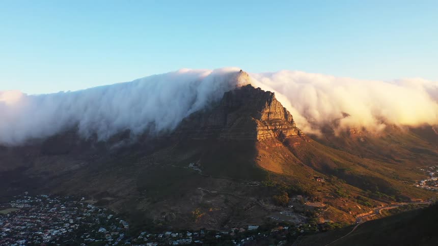 An aerial view shows table mountain shrouded in clouds at sunset
