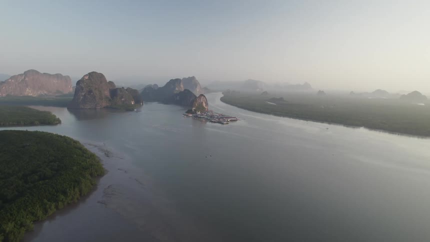 A small village perched on stilts above the water nestled amongst cliffs and shrouded in morning mist