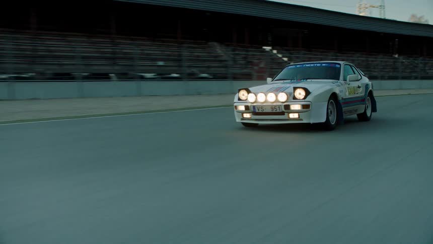 Sports car with headlights on racing down a race track