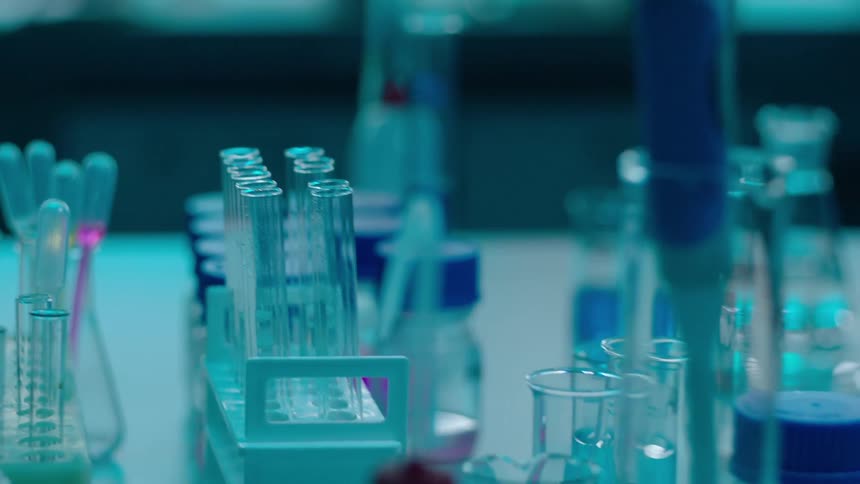 Person wearing gloves uses a test tube in a lab