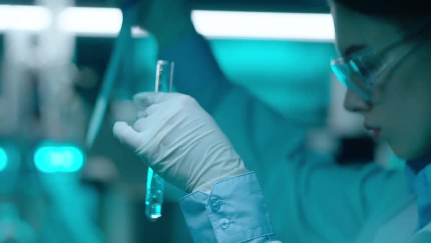 Woman in a laboratory working with test tubes wearing gloves and protective glasses