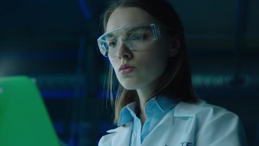 Female researcher taking notes on a clipboard inside a lab