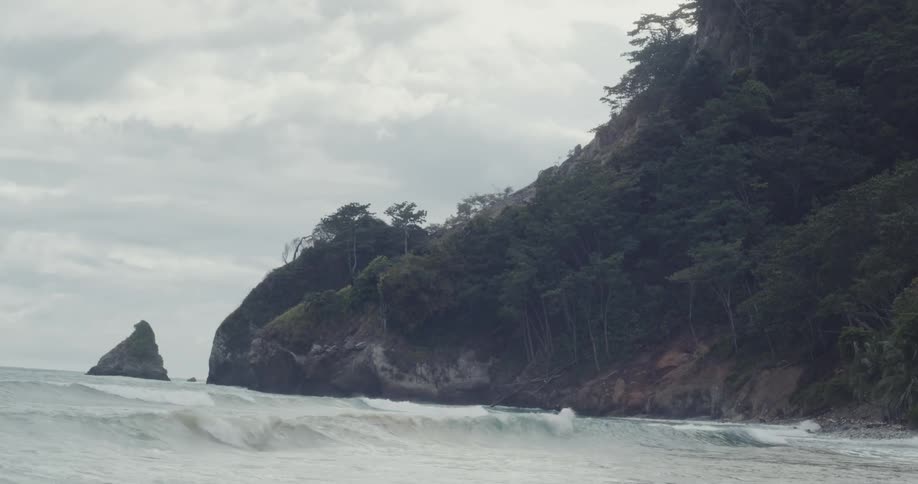 Beach with calm waves and the wooded coast in the background