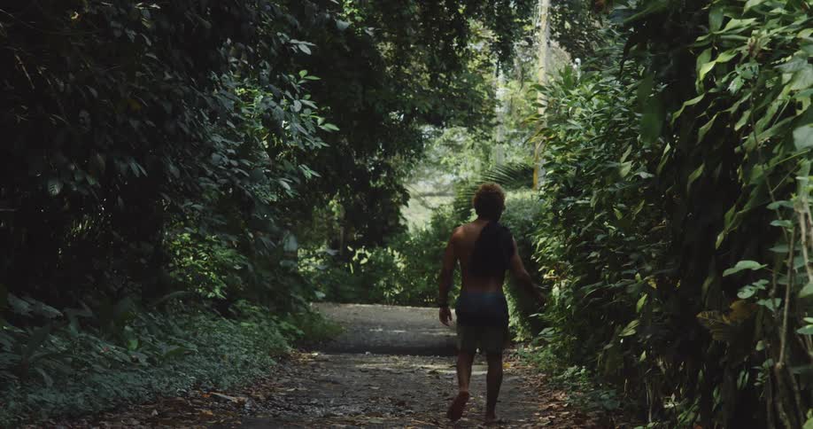 A man walks on the trail with his shirt on his shoulder